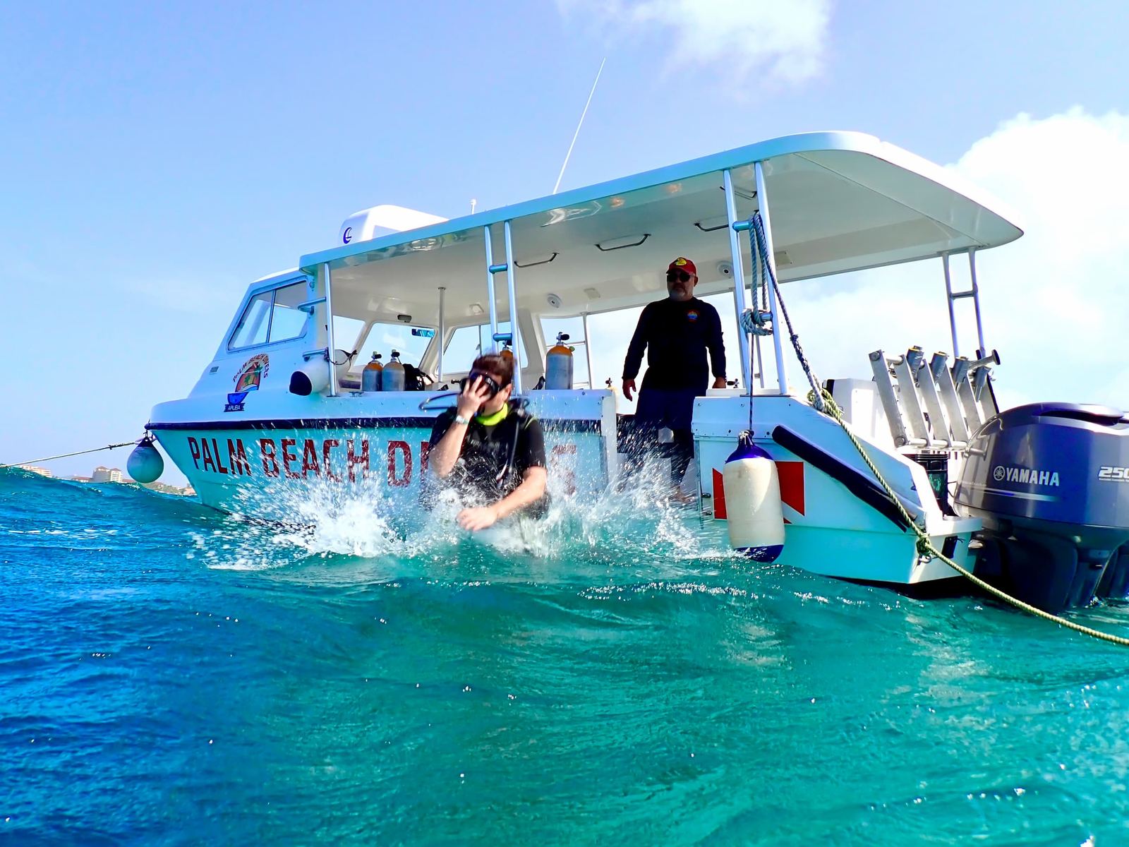 A diver splashing into turquoise water from the boat