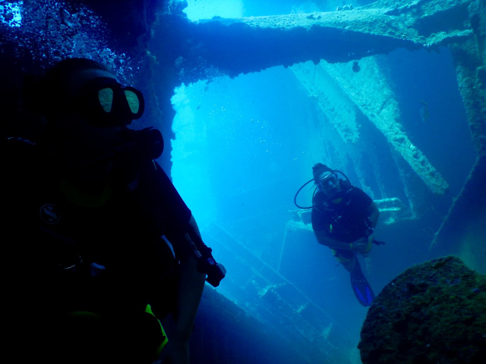 Divers inside a wreck, light coming through the hull